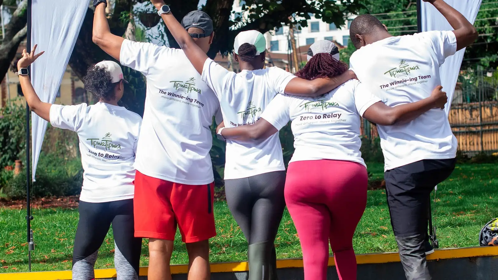 Four TipwaTipwa members running the relay with their arms around each other