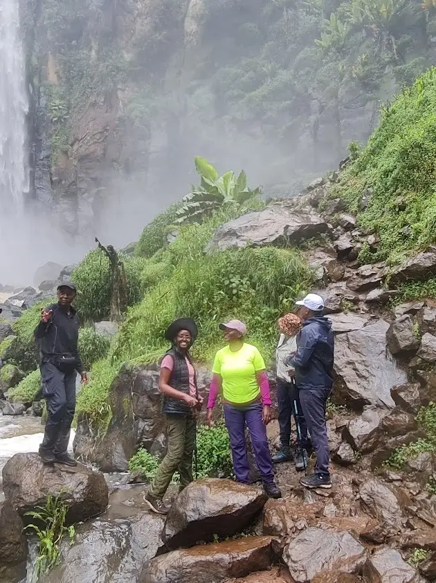 Hikers dwarfed by a waterfall on a TipwaTipwa trek